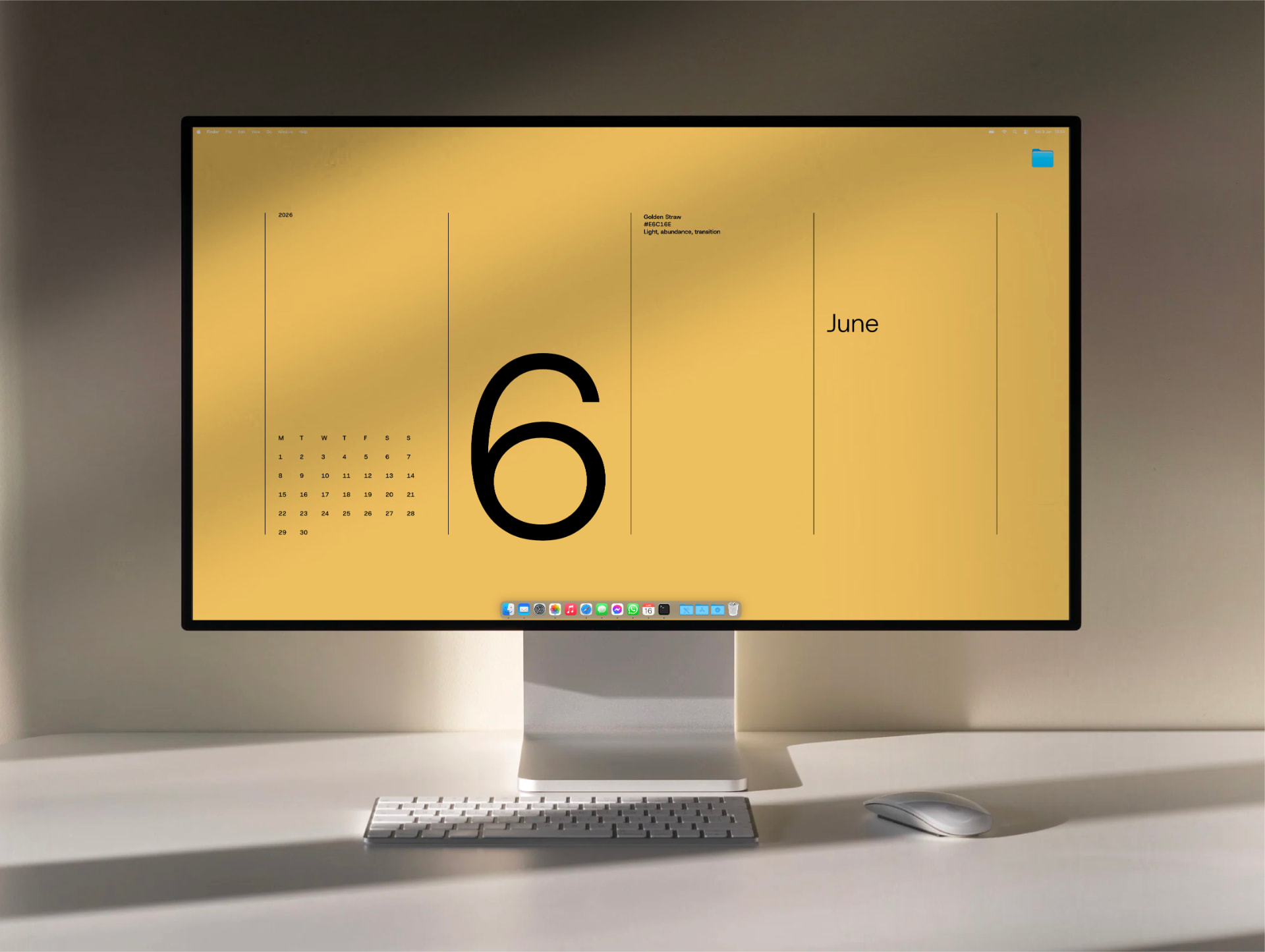 The June wallpaper in Golden Straw on a large desktop display on a white desk